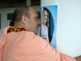 Джаяпатака Свами обнимает колону с плакатом, на котором изображен Джаянанда, со словами: «Мой любимый вартма-прадаршака-гуру» 