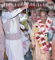 Джаянанда держит зонт над Шрилой Прабхупадой во время встречи в аэропорту   